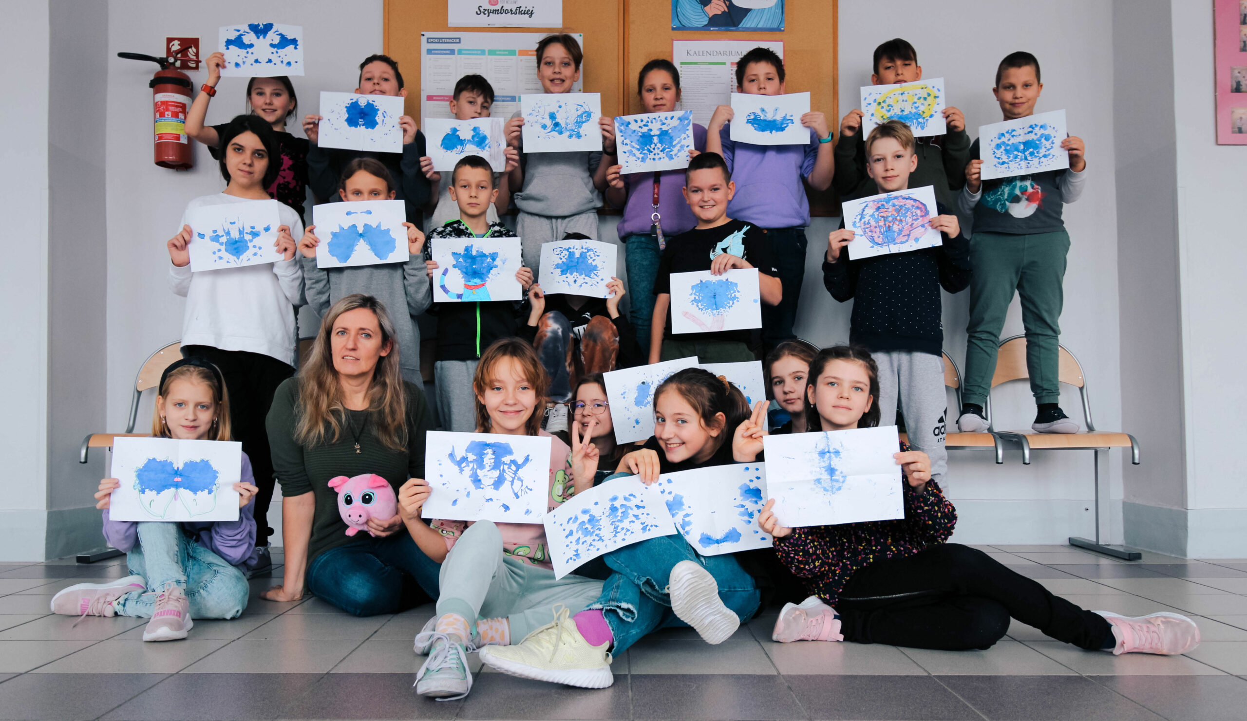 Zdjęcie przedstawia uczniów klasy 4a wraz z wychowawcą podczas lekcji kleksografii.