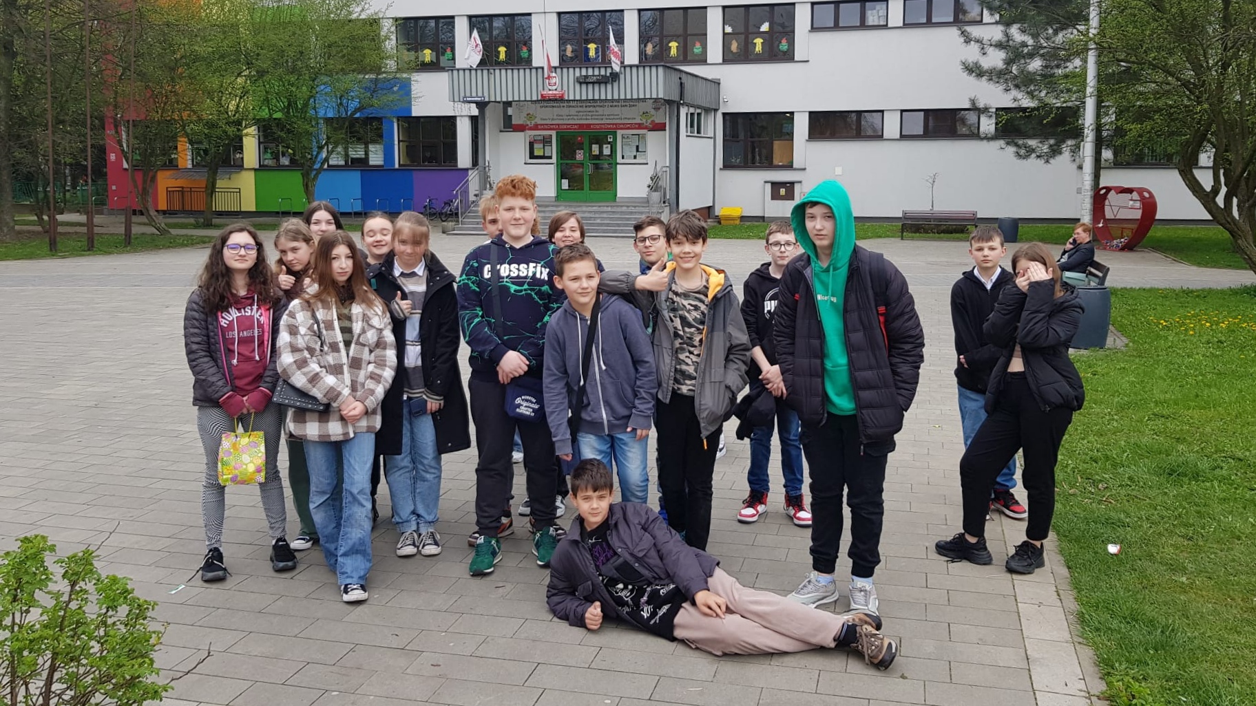 Uczniowie i uczennice przed budynkiem szkoły.